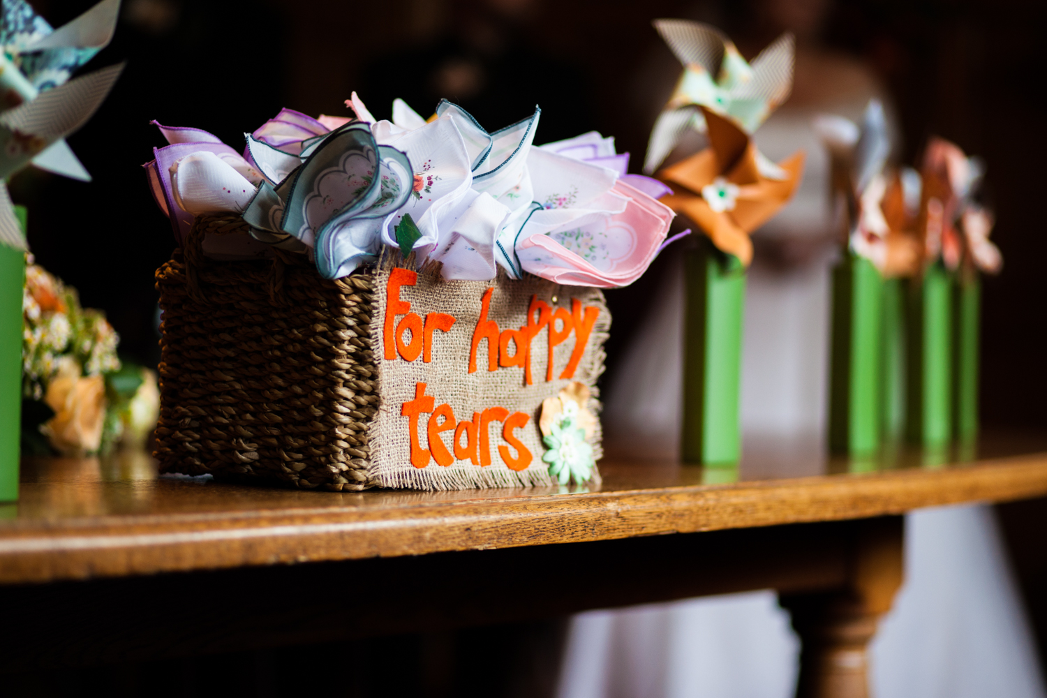 Basket of vintage handkerchiefs labelled 'For happy tears' on a wedding ceremony table