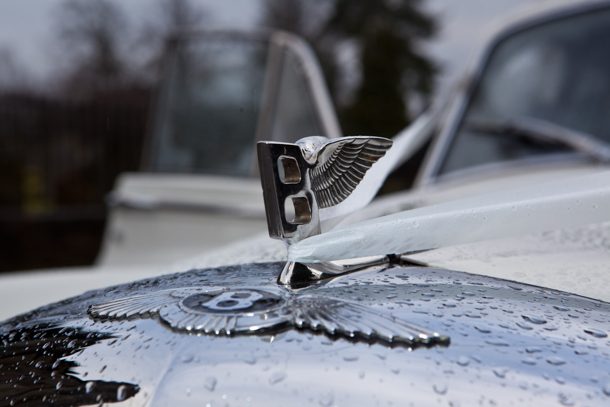 Rain beaded on the bonnet of a vintage white wedding car