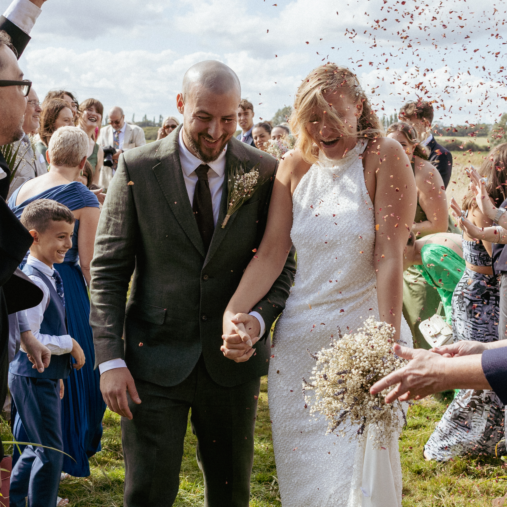 Confetti thrown over a bride and groom walking hand in hand through their guests